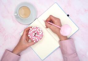 el niña calcula en un cuaderno el calorías de un rosquilla y un taza de café foto