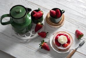 Fruit still life with strawberries and green tea set, strawberry cake with cream photo