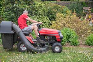 césped cortacésped corta el césped, un de edad mediana masculino jardinero trabajos en un mini tractor foto