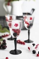 transparent gin and tonic with ice and fresh red currants and blackberries photo