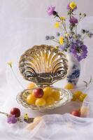 delicate still life with yellow and red cherry plum berries in a special crystal vase in the shape of a shell photo