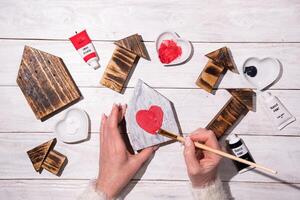 woman drawing heart on wooden house, crafting, step by step instructions how to make decor for valentines, mothers day photo