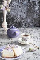 todavía vida con negro té y queso pastel, primavera ramo, delicado lila flores foto