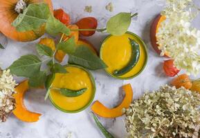 Pumpkin puree soup in green bowls on gray cement background, colorful food, photo