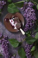 melted raspberry ice cream in chocolate on a wooden stick on a dark table photo