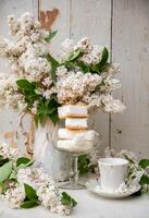 spring still life, a stack of waffle ice cream in a bowl and on a saucer, with a bouquet of white lilacs in tea pot photo