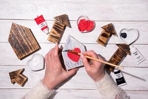 mujer dibujo corazón en de madera casa, elaboración, paso por paso instrucciones cómo a hacer decoración para san valentin, madres día foto