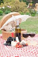 verano picnic en un verde césped con rojo vino, queso y Fresco bayas, uvas foto