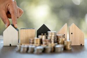 Model of house with stack coins on table on blurred background. Money saving or investing for home loan or real estate. Investment property, Saving money for retirement concept. photo