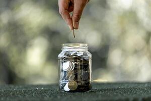 Saving money concept preset by female hand putting money coin in jar, growing business. Planning budget, investment strategy, saving money, checking finances photo