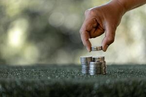 Saving money concept preset by female hand putting money coin stack growing business. Asian woman making stack of coin, planning budget, investment strategy, saving money, checking finances photo