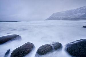 Waves of Norwegian sea surging on stone rocks. Long exposure photo