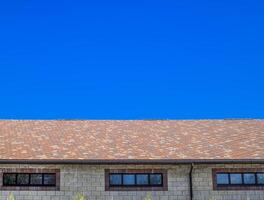 The house is made of beige bricks, the roof is covered with bitumen shingles. Metal plastic windows on the house. photo