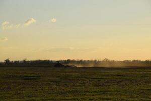 Tractor at sunset plow plow a field. Tilling the soil in the fall after harvest. The end of the season photo