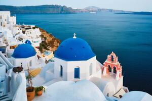 Famous view from viewpoint of Santorini Oia village with blue dome of greek orthodox Christian church photo