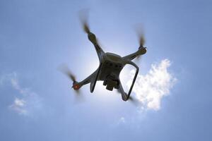 Drone DJI Phantom 4 in flight. Quadrocopter against the blue sky with white clouds. The flight of the copter in the sky. photo