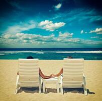 Couple in beach chairs holding hands near ocean photo