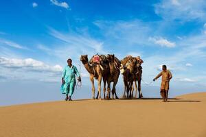 Two cameleers camel drivers with camels in dunes of Thar desert photo