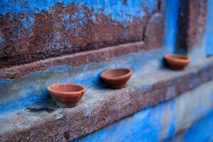 Oil Lamp Pooja Diya Lamp on blue house wall in Jodhpur, Rajasthan, India photo