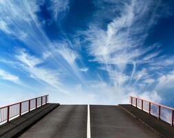 Asphalt road going into sky with clouds photo