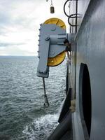 A large mooring line with rollers at the stern of the ship. A man next to the rollers of a barge mooring line. photo