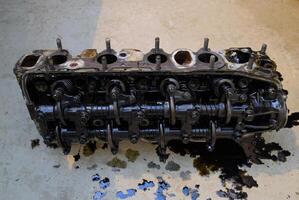 The head of the block of cylinders. The head of the block of cylinders removed from the engine for repair. Parts in engine oil. Car engine repair in the service photo