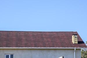 Roof from multi-colored bituminous shingles. Patterned bitumen shingles. Bituminous burgundy roof. photo