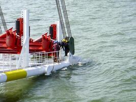 Laying of pipes with pipe-laying barge crane near the shore. Descent of the pipeline to a bottom exhausting with the pipelaying barge. Installation of the underwater gas pipeline photo