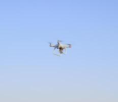 White drone against the blue evening sky. Multicopter flight. photo