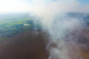 The smoke over the village. Clubs of smoke over the village houses and fields. Aerophotographing areas photo