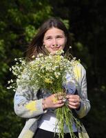 joven hermosa niña con un ramo de flores de manzanilla un mujer en un cebada campo foto