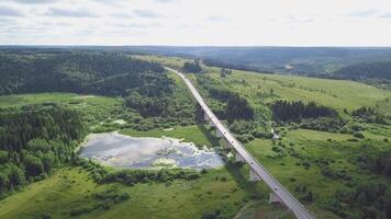 Top view of traffic on rural road in forest. Clip. Highway passing through swamp in forest with cloudy sky video