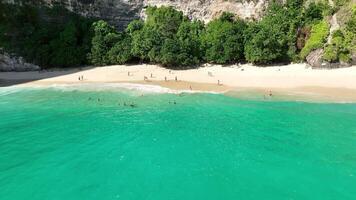 tropical island beach people walking cliff kelingking nusa penida bali aerial 4k video