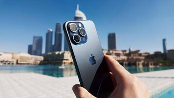 Dubai - Verenigde Arabisch emiraten, januari 18, 2023. dichtbij omhoog van mannetje hand- Holding nieuw appel iphone tegen water fonteinen in Dubai stad. actie. mooi panorama van een modern beroemd stad. video