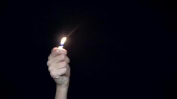 Hand with lighter. Close-up of waving hand with burning lighter. Flame lighter a symbol of remembrance or love of fans at concerts. Black isolated background video