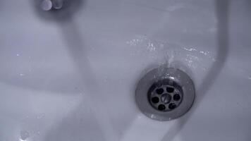 Close-up of sink drain. Water stikaet to stoke white new washbasin. Washing in morning. Morning routine video