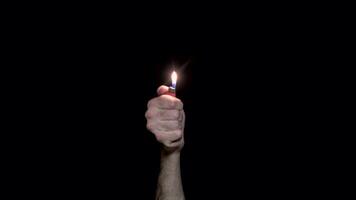 Close-up of man's hand lit lighter. Lit lighter on black background. Light in dark symbol of memory and solidarity video