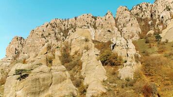 parte superior ver de alto montaña rango en vistoso otoño con verde amarillo prados y rocoso montaña picos disparo. ver de rocoso terreno de montañas. magnífico montaña paisaje en contra claro azul cielo video