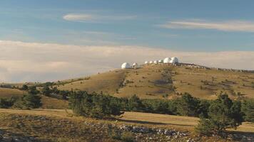 parte superior ver de blanco abovedado edificios de observatorios en colina. disparo. astronómico investigación instalaciones y grande observatorios situado a parte superior con hermosa puesta de sol cielo y nubes video