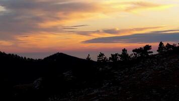 noir silhouette de colline à le coucher du soleil avec des nuages. tir. Haut vue de pittoresque le coucher du soleil. ciel est peint dans brillant couleurs sur vallonné terrain video