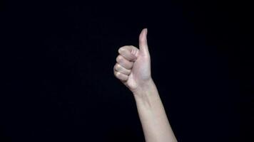 Hand sign meaning like. Close-up of thumb sign up. Good hand gesture. Black isolated background video