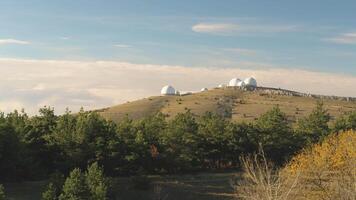 topp se av vit kupol av observatorium på topp av kulle. skott. panorama- se av astronomisk observatorium komplex i vild mot blå himmel med moln. begrepp av radio astronomi video