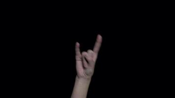 Close-up of hand with rock sign. Female hand showing gesture on black background. Goat gesture denoting declaration of love or approval of rock music video