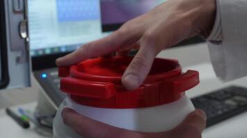 Chemical scientist opening white unlabeled plastic tank canister with chemicals on laboratory table video