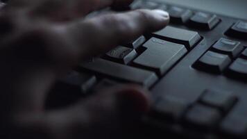 Close-up man presses keyboard key. Man presses button enter computer keyboard. Man's hand presses keyboard in light of computer screen video