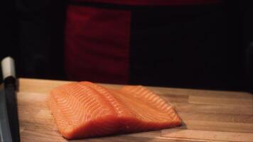 Close-up of raw salmon fillet on wooden board with knife. View of juicy piece of salmon before cutting to prepare delicious dish video