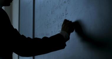 Scientist writing formulas on chalkboard. Hand with chalk wrote physics formulas on black chalkboard closeup video