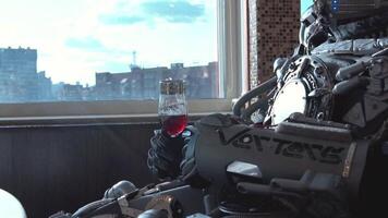 Metal android sitting at table in restaurant with glass of wine on background of view of high-rise buildings of city. Footage. Robot man behaves like human. Technology concept video