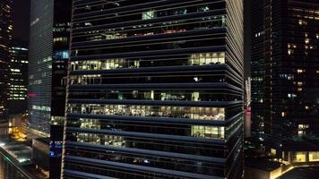 exterior pintoresco moderno rascacielos con brillante ventanas de oficinas en noche. disparo. el concepto de la vida nocturna en metrópoli. parte superior ver de oficinas de Alto construyendo en noche video