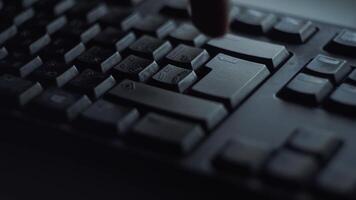 Close-up man presses keyboard key. Man presses button enter computer keyboard. Man's hand presses keyboard in light of computer screen video